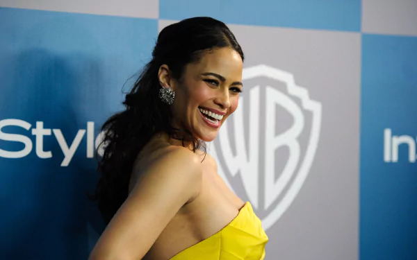 HD desktop wallpaper featuring American actress and celebrity Paula Patton smiling in a yellow dress against a blue event backdrop.