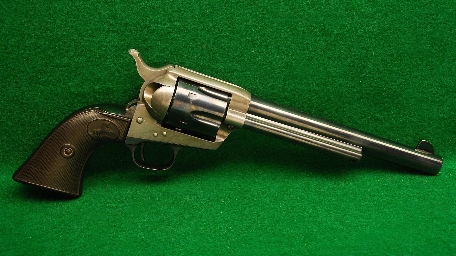 HD desktop wallpaper of a man-made Colt revolver with a wooden grip, displayed against a green background.