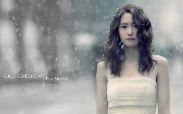 HD PC desktop wallpaper: a K-pop music idol from a girl group stands in falling snow with a soft-focus winter background, calm and ethereal portrait.