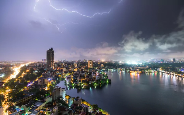 HD desktop wallpaper showing lightning striking over the man-made skyline of Hanoi, Vietnam, with city lights reflecting on the river at night.