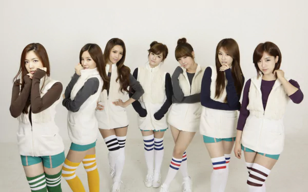 HD PC desktop wallpaper of seven women in coordinated white vests and colorful striped knee-high socks, posing together in a music-themed pop group photo.
