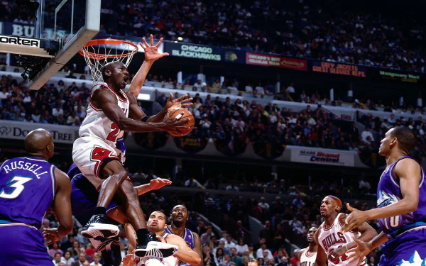 Michael Jordan soars for a slam dunk during a Chicago Bulls game, showcasing his athleticism and skill amidst a crowded arena, capturing the essence of competitive basketball.