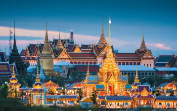 HD PC desktop wallpaper of Bangkok's Grand Palace, Thailand, at dusk — ornate golden spires and tiled roofs glowing across the man-made temple complex.