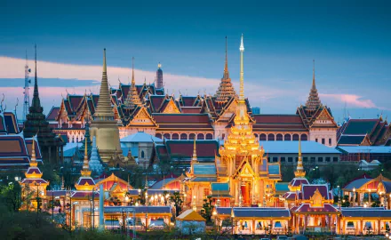 HD PC desktop wallpaper of Bangkok's Grand Palace, Thailand, at dusk — ornate golden spires and tiled roofs glowing across the man-made temple complex.