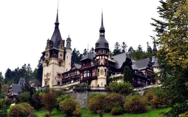 Peles Castle in Romania, a stunning man-made historic landmark surrounded by greenery, captured in high definition for a PC desktop wallpaper.