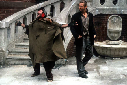 HD wallpaper featuring a scene from The Fisher King with two characters walking in front of an urban fountain.