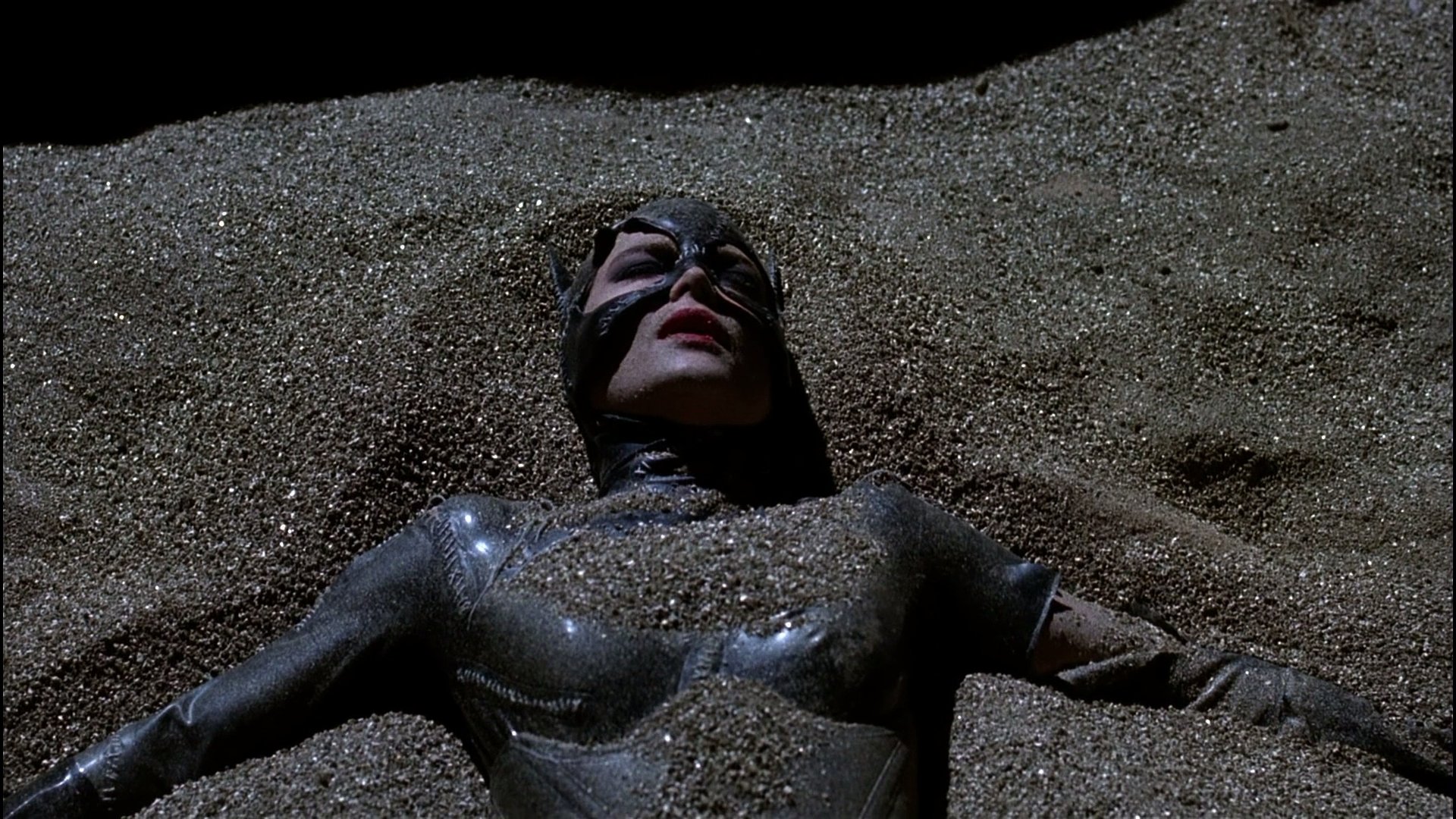 Catwoman from Batman Returns lying in glittering sand, glossy black suit and mask — HD PC desktop wallpaper/background.