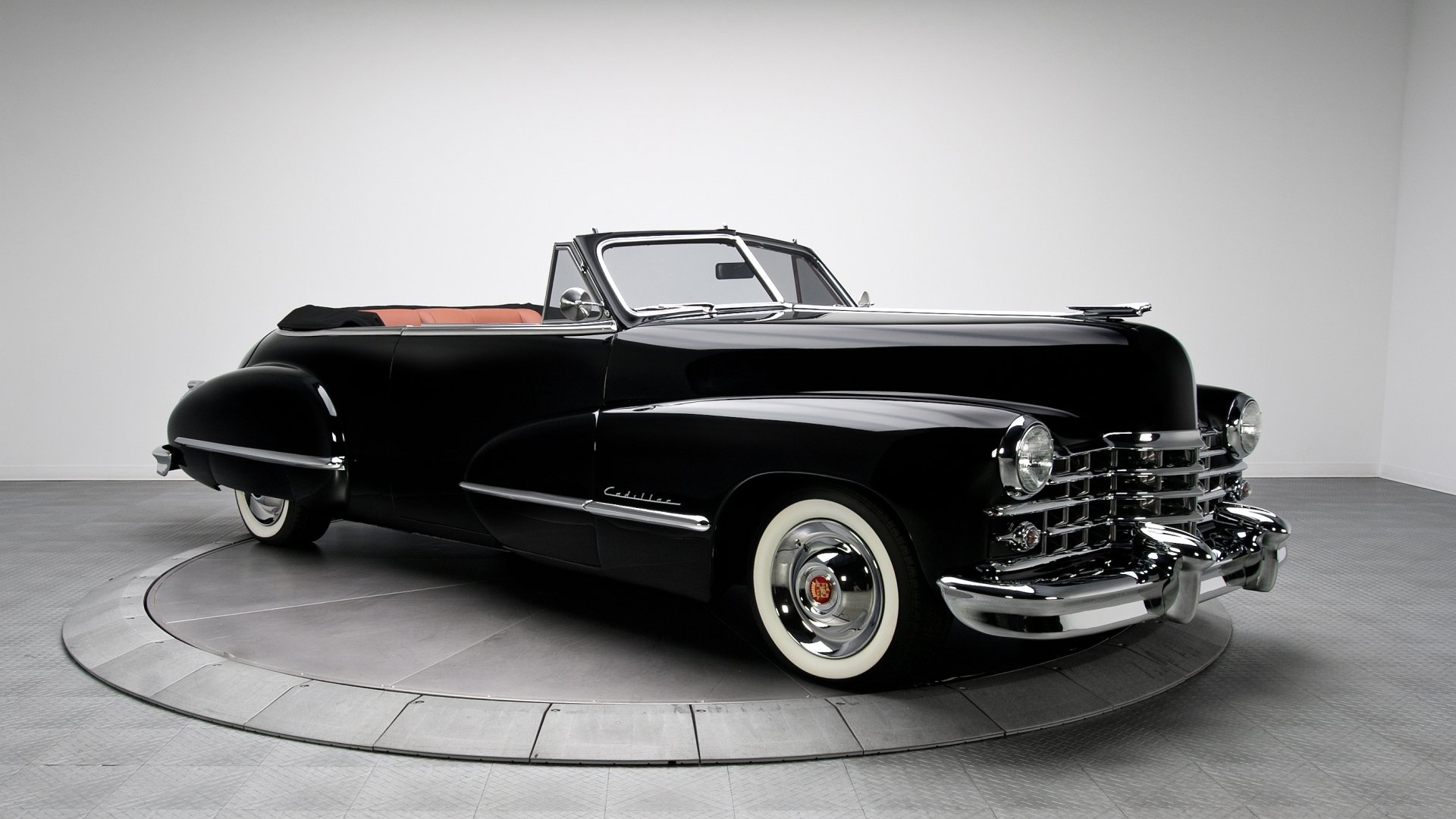 HD desktop wallpaper featuring a sleek black Cadillac convertible car in a studio setting with a clean white background.