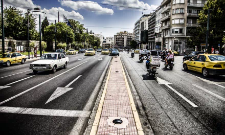 5K Ultra HD PC desktop wallpaper: night Greek city street, broad road with taxis, scooters and buildings, moody urban photography background.