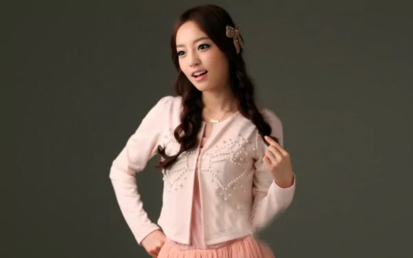 HD Korean K-pop music desktop wallpaper showing a female idol in a pink dress and cardigan, posing against a neutral gray background.