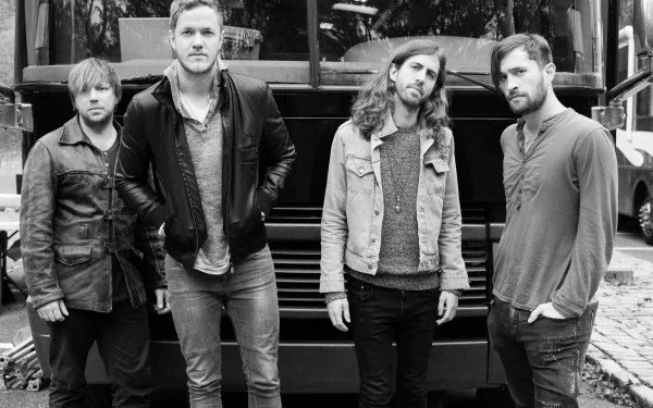 A black and white image of the band Imagine Dragons posing in front of a tour bus, showcasing their style and camaraderie. This serves as a striking HD wallpaper for music fans.