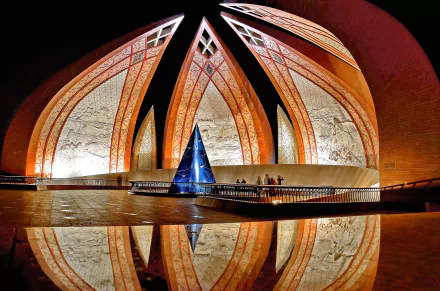 Stunning view of the Pakistan Monument in Islamabad, showcasing its unique architectural design illuminated against the night sky, reflected in tranquil waters.