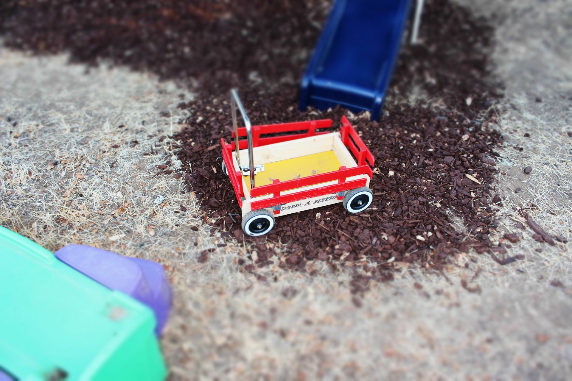 HD desktop wallpaper of a toy wagon on a playground with wood chips, showcasing playful colors and childhood nostalgia.