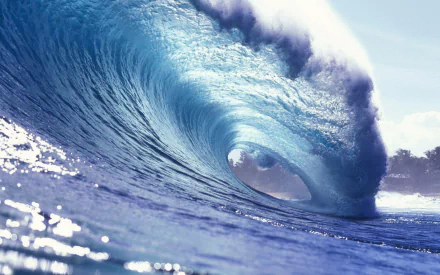 A stunning HD wallpaper showcasing a majestic wave, capturing the beauty and power of nature with vibrant blue tones and sunlight reflecting off the water surface.
