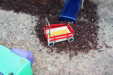 HD desktop wallpaper of a toy wagon on a playground with wood chips, showcasing playful colors and childhood nostalgia.