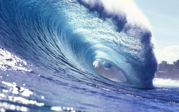 A stunning HD wallpaper showcasing a majestic wave, capturing the beauty and power of nature with vibrant blue tones and sunlight reflecting off the water surface.