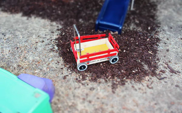 HD desktop wallpaper of a toy wagon on a playground with wood chips, showcasing playful colors and childhood nostalgia.