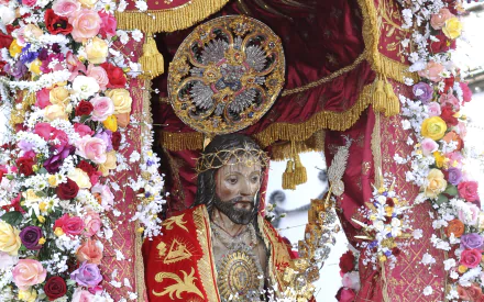 A detailed depiction of a religious statue of Jesus, adorned with vibrant flowers and rich fabrics, serving as a striking HD PC desktop wallpaper and background.