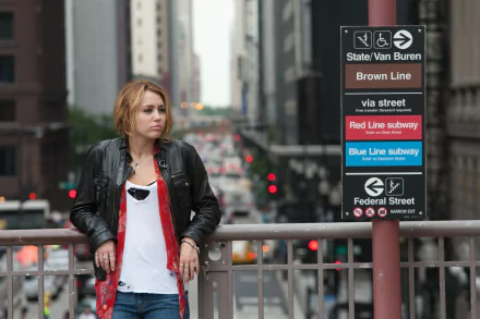 4K Ultra HD wallpaper of singer and actress Miley Cyrus from the movie LOL, standing on a city street near subway signs for Brown, Red, and Blue Lines.