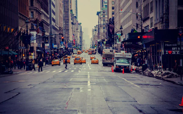 HD cityscape wallpaper of a busy New York street lined with tall buildings and yellow taxis in the USA, capturing the vibrant urban atmosphere.