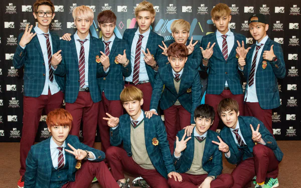 HD desktop wallpaper featuring EXO, a popular music group, in matching outfits posing at an event with a logo-covered backdrop.
