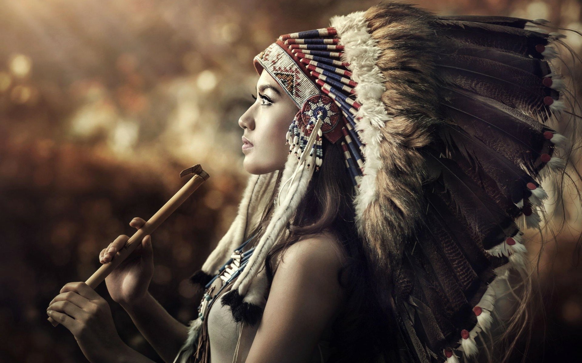 HD desktop wallpaper featuring a woman in Native American attire playing a flute, set against a softly blurred autumnal background.