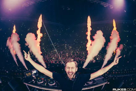 HD PC desktop wallpaper featuring Calvin Harris performing live, arms raised amid pyrotechnics and a vibrant crowd, capturing the energy of a music festival.