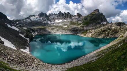 A stunning HD desktop wallpaper showcasing a serene alpine lake surrounded by rugged mountain ridges under dramatic cloud-filled skies in the Alps.