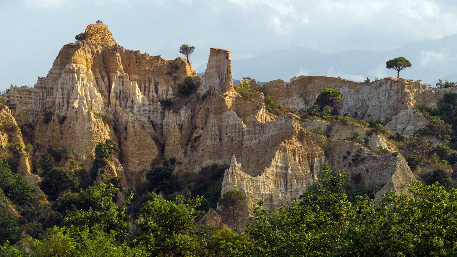 4K Ultra HD landscape showing rugged rock formations rising above lush greenery under a bright sky, capturing the beauty of nature in vivid detail.