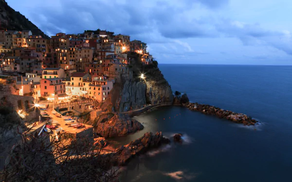 Night view of Manarola’s illuminated cliffside buildings overlooking the sea, captured in stunning 4K Ultra HD for a vibrant PC desktop wallpaper.