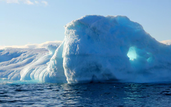 4K Ultra HD PC desktop wallpaper showing a luminous blue iceberg arch rising from calm sea beneath a clear sky — nature, iceberg.