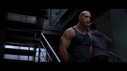 HD PC desktop wallpaper from the movie Doom: a muscular man in a black tank top stands by metal stairs in a dim industrial sci‑fi corridor.