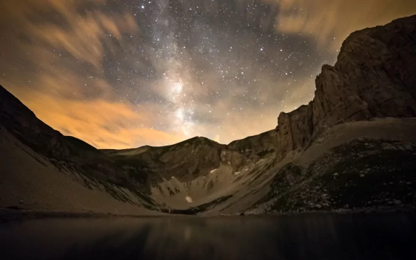 4K Ultra HD sci-fi desktop wallpaper showcasing the Milky Way arching over rugged mountain cliffs under a starry night sky.