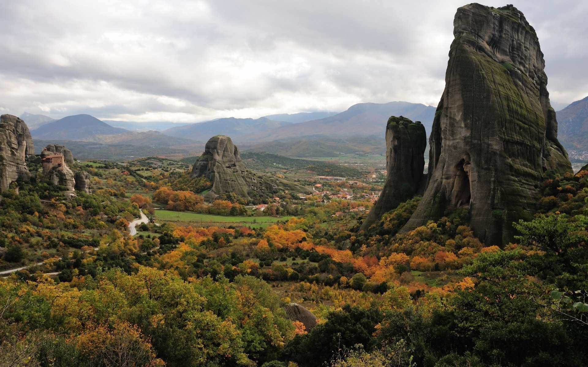 A magical mountain landscape features towering rock formations amidst a vibrant, autumnal valley, capturing the enchanting beauty of nature in stunning HD detail.