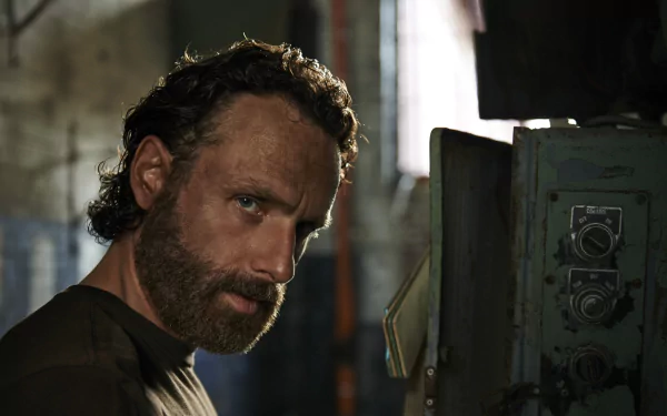 A close-up of Andrew Lincoln as Rick Grimes from The Walking Dead, featuring a rugged expression against a gritty background, captured in high-definition wallpaper format.