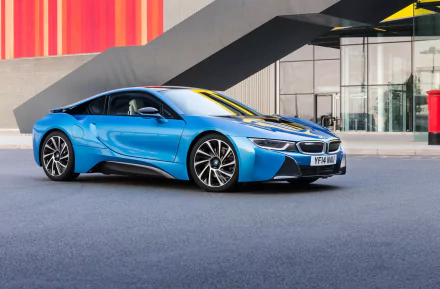 A sleek blue BMW i8 parked in an urban setting, showcasing its futuristic design against a modern architectural backdrop. A striking HD desktop wallpaper and background.