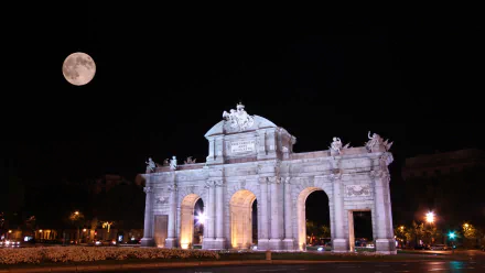Night view of the man-made Puerta de Alcalá monument illuminated under a full moon, captured in HD for a PC desktop wallpaper and background.