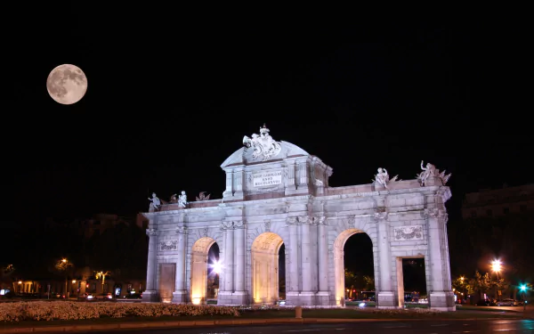 Night view of the man-made Puerta de Alcalá monument illuminated under a full moon, captured in HD for a PC desktop wallpaper and background.