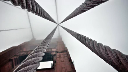 A 4K Ultra HD desktop wallpaper capturing the vertical perspective of the man-made Golden Gate Bridge cables and tower disappearing into fog.