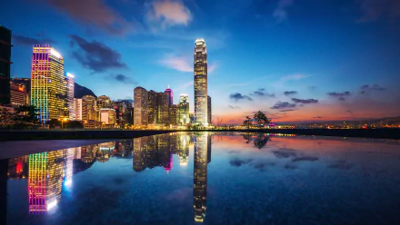 HD wallpaper of Hong Kong's cityscape at twilight, featuring illuminated buildings reflected in water under a colorful sky.