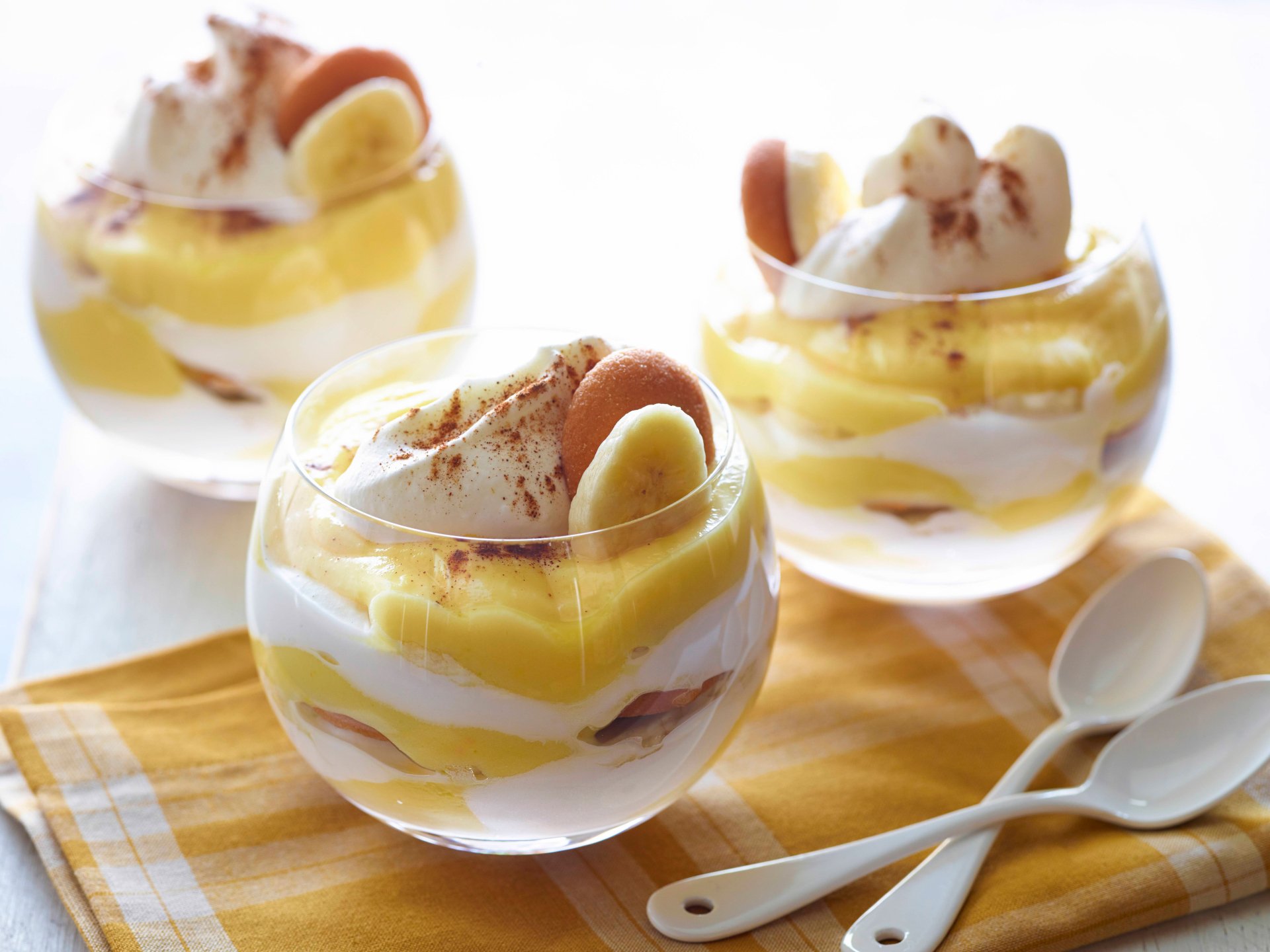 Close-up of creamy banana pudding layered with whipped cream and banana slices in glass bowls, captured in 4K Ultra HD for a vibrant PC desktop wallpaper.