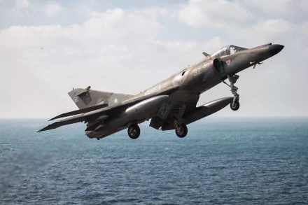 HD PC desktop wallpaper of a Dassault-Breguet Super Étendard jet fighter — a military air force aircraft in flight over the ocean with landing gear down.
