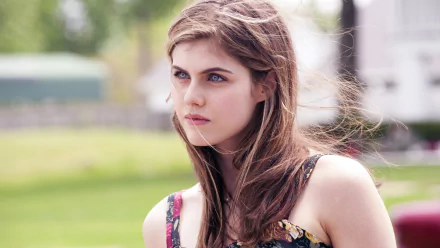 HD desktop wallpaper featuring Alexandra Daddario standing outside, with a green blurred background, highlighting her intense expression and casual attire.