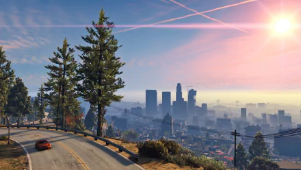 HD wallpaper of Grand Theft Auto V featuring a scenic view of a car driving on a winding road with a city skyline in the background, under a vibrant sky at sunset.