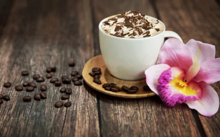 A cappuccino topped with chocolate shavings sits on a wooden surface, surrounded by coffee beans and a vibrant orchid flower, creating a cozy coffee-themed background.