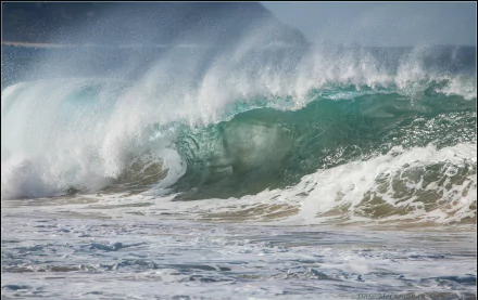 HD PC desktop wallpaper and background — nature wave: a turquoise ocean swell curling into a frothy barrel as it crashes onto a sandy shore beneath a misty sky.