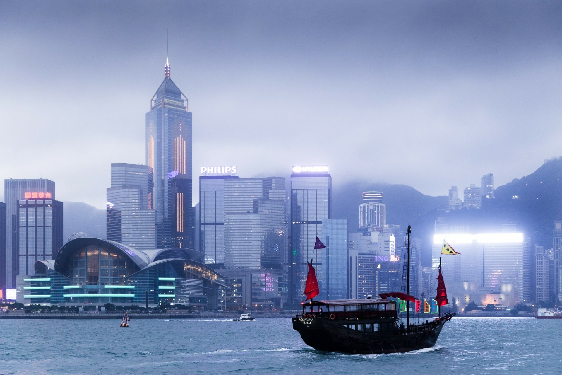 Foggy view of Hong Kong's man-made skyline with a traditional junk boat sailing in the foreground, captured in high-definition as a PC desktop wallpaper background.