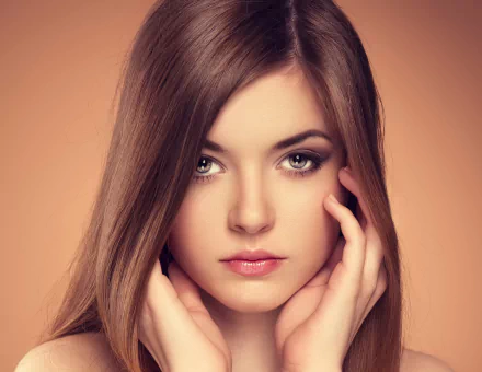 HD desktop wallpaper features a woman with long brown hair, her face framed by her hands, set against a soft brown background.