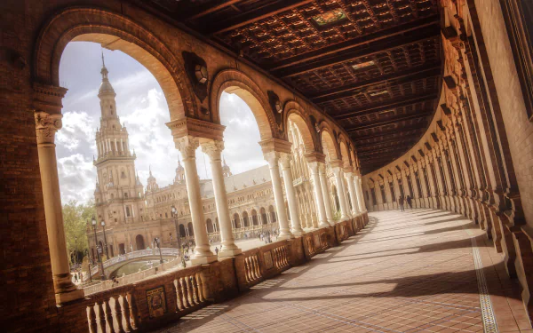 View of the ornate arches and tower at Plaza de España, a man-made landmark in Seville, Spain, captured in an HD desktop wallpaper style.