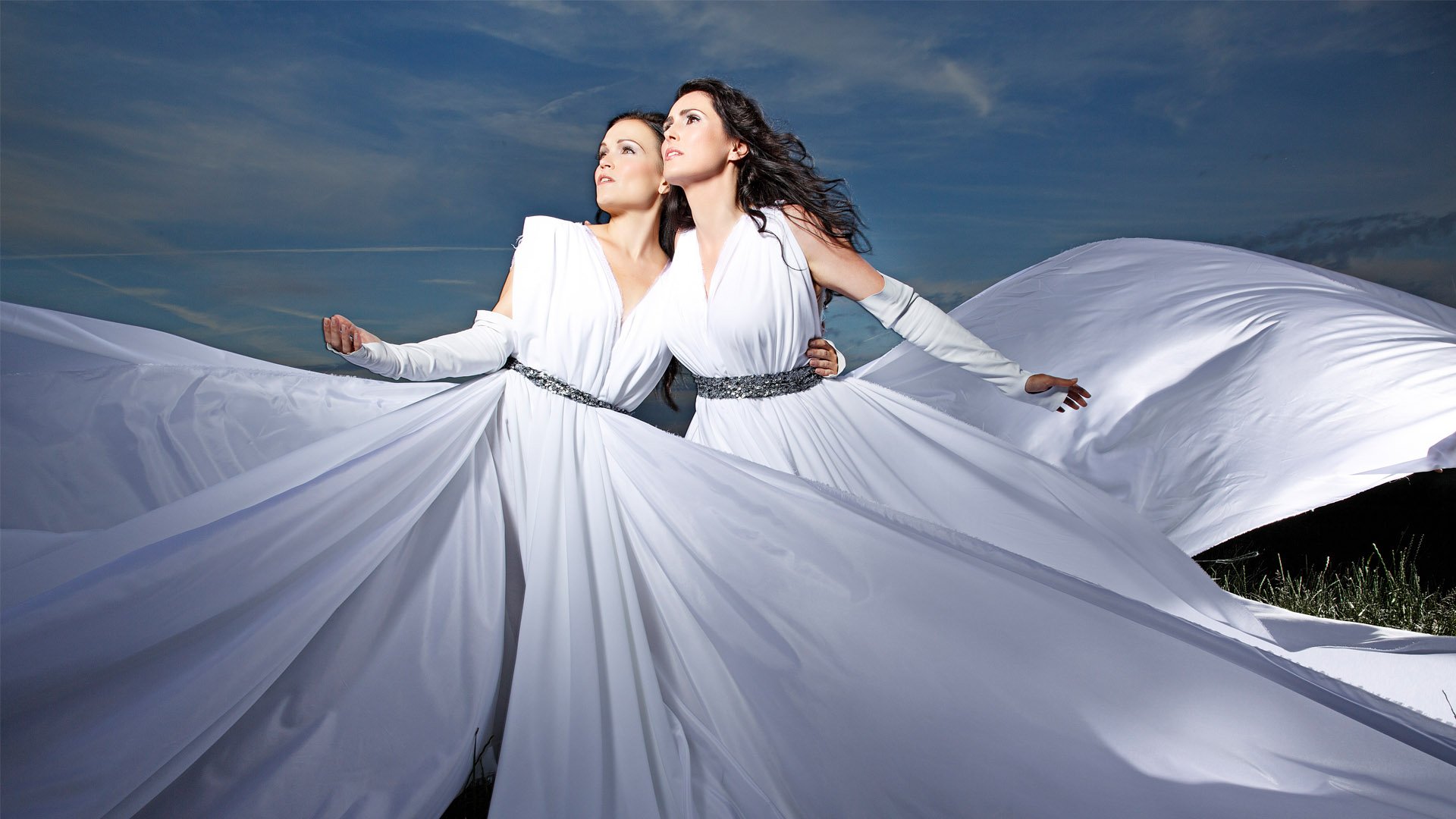 HD PC wallpaper: two women in flowing white gowns beneath a stormy sky, evoking Within Temptation's dramatic, music-themed aesthetic.